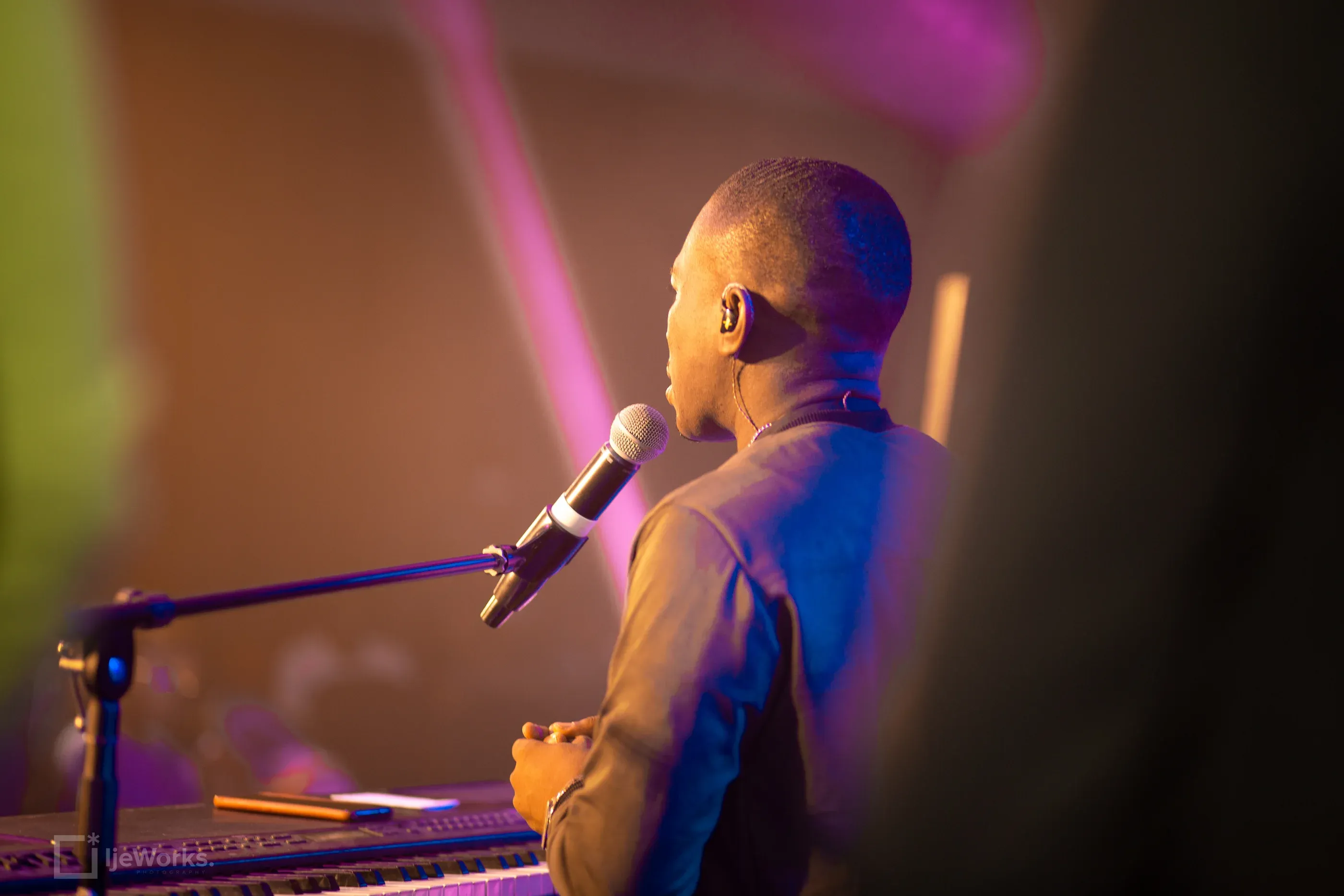 David Nkennor leading worship at a keyboard under stage lighting.
